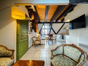 Een gezellige woonkamer met een groene deur, een eethoek met een tafel en stoelen, en een keuken op de achtergrond.