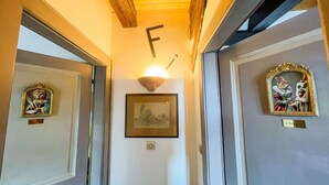 A hallway with a framed picture on the wall, a door with a 'F' sign, and a door with a framed painting. - La Maison Bleue - Historic house in the heart of Riquewihr. 5 guest apartment (Riquewihr)