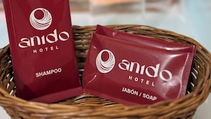 A wicker basket containing two red Amido Hotel shampoo and soap packets. - Anido Hotel (Ollantaytambo)