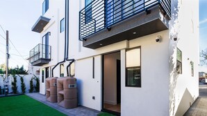 A modern two-story building with a flat roof, large windows, and a balcony with a metal railing. - Modern Luxe Retreat#3 Three-Bedroom (Los Angeles)
