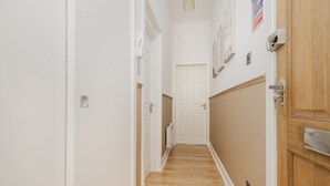 A hallway with wooden flooring, white walls, and a white door at the end.