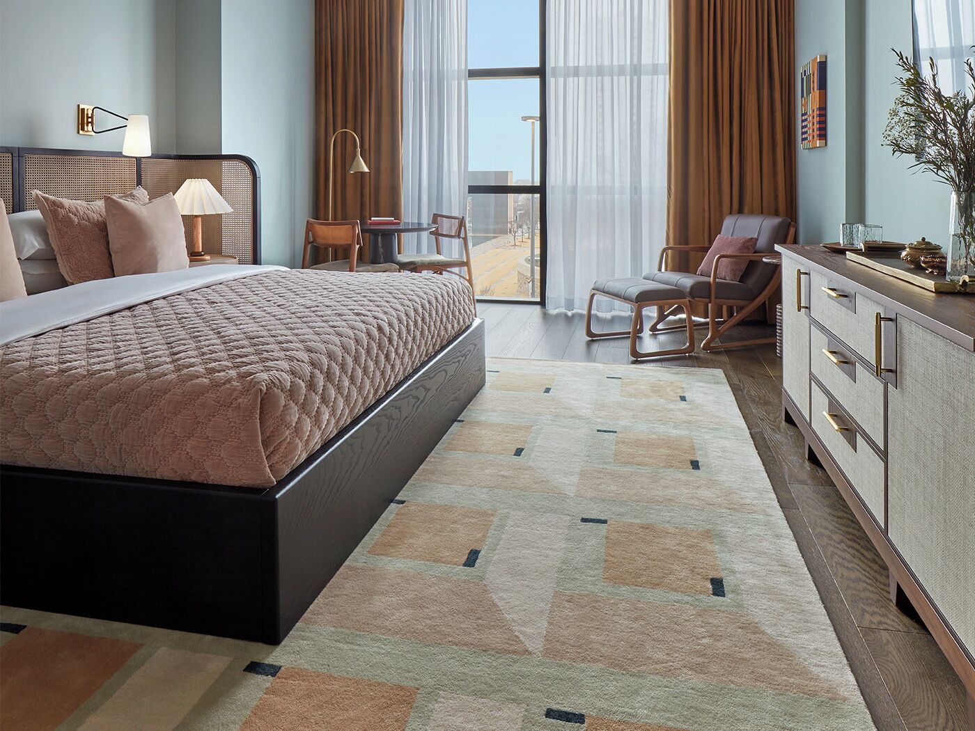 A modern hotel room with a large bed, a desk, and a view of the city.