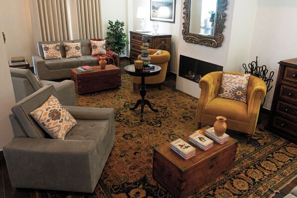 A living room with a sofa, armchair, and a small table with books and a vase. - Katari Atojja Puno Hotel (Chucuito)