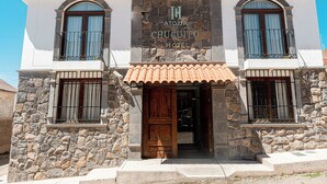 Un hotel con fachada de piedra, dos balcones y techo de tejas.
