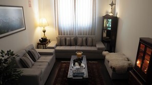 A living room with a sofa, a coffee table with books, a lamp, and a decorative item. - Katari Atojja Puno Hotel (Chucuito)