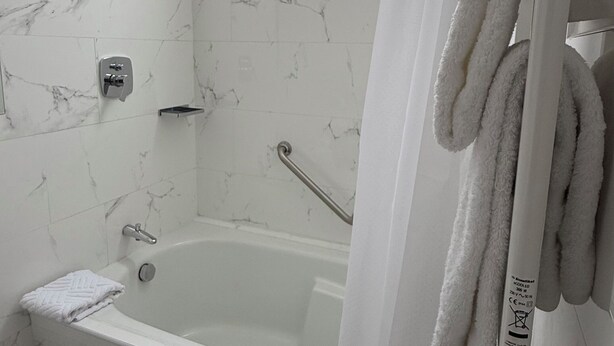 A bathroom with a bathtub, a shower, and a toilet. There is a towel rack with towels hanging on it. - Katari Atojja Puno Hotel (Chucuito)