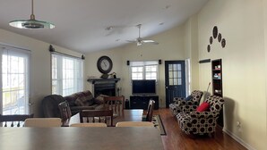 A spacious living room with a dining table, sofas, a fireplace, and a television. - Mountain home in Newland (Newland)