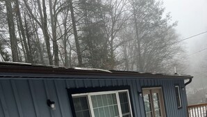 A building with two windows and a covered porch area with chairs. - Mountain home in Newland (Newland)