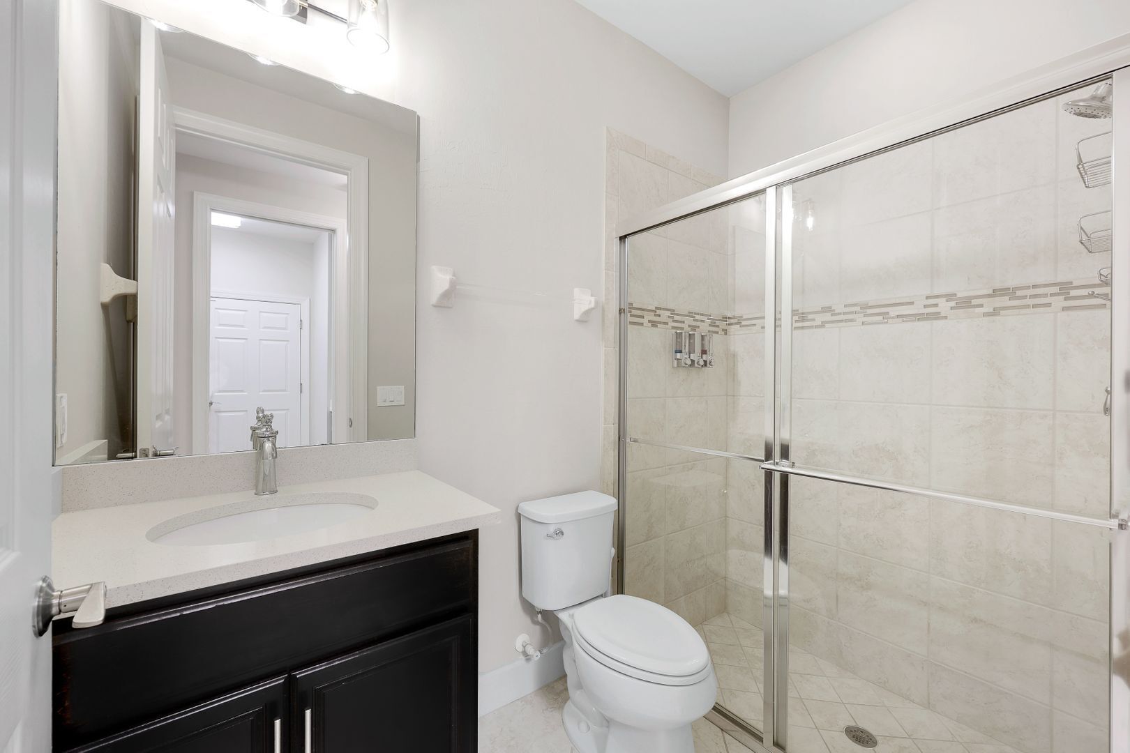 A bathroom with a white sink, a toilet, and a glass-enclosed shower.