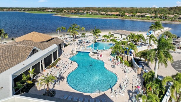 Un complexe hôtelier doté d’une grande piscine, de palmiers et offrant une vue sur l’eau.