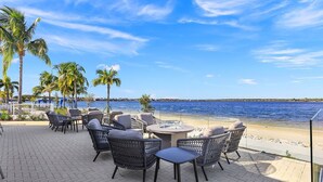 Un espace extérieur aménagé avec des chaises et des tables en osier, offrant une vue sur la plage et la mer.