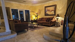 A living room with two sofas, a coffee table, a lamp, and a painting on the wall. - The Art History House, indoor heated pool, 3 bedrooms, with two kitchens (Goose Creek)