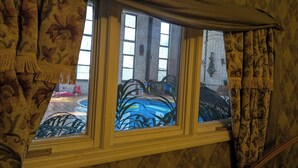 A room with a large window, a view of a blue pool, and a brick wall. - The Art History House, indoor heated pool, 3 bedrooms, with two kitchens (Goose Creek)