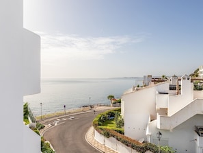 Une route côtière avec un bâtiment blanc sur la droite, doté d’une allée sinueuse et d’un petit jardin.