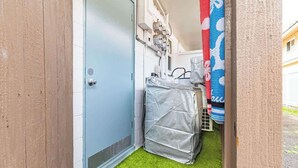 Ein schmaler Flur mit einer blauen Tür, einem bedeckten Gegenstand und einem blau-weißen Muster an der Wand.