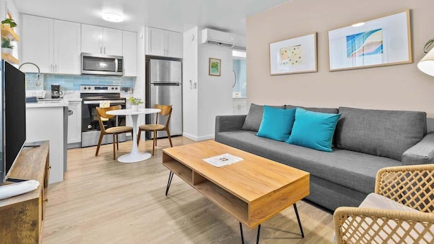 Ein stilvoller Wohnraum mit grauem Sofa, Holztisch und Korbstühlen.