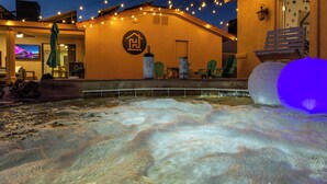 Ein Poolbereich mit Wasserspiel, Sitzmöglichkeiten im Freien und Lichterketten.