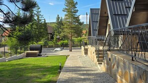 A pathway leading to a building with a sloped roof and a stone wall.