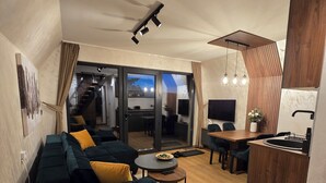 A modern living room with a sofa, a dining table, and a kitchen area with a sink.