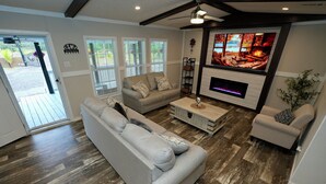 Un salon moderne avec une cheminée, un canapé, une table basse et un téléviseur.