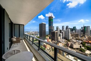 A balcony with a view of a cityscape, including high-rise buildings and a waterfront.
