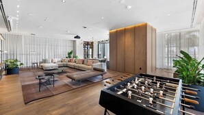 A spacious living room with a sofa set, a foosball table, and a coffee table.