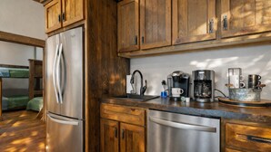 A kitchen with wooden cabinets, stainless steel appliances, and a coffee maker. - Creek Haüs: Cozy Retreat w/ Endless Entertainment • HotTub • FirePit • GameRoom (Blue Ridge)