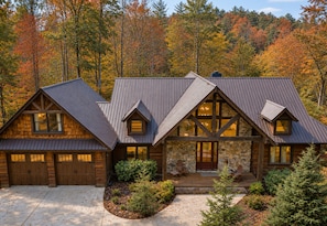 A log cabin with a stone foundation, large windows, and a covered porch.