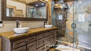 A bathroom with a wooden vanity, a large mirror, and a stone shower enclosure. - Creek Haüs: Cozy Retreat w/ Endless Entertainment • HotTub • FirePit • GameRoom (Blue Ridge)