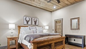 A bedroom with a wooden bed, two bedside lamps, a wooden bench, and a mirror on the wall.