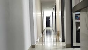 En lång, smal hall med vita väggar och ett glänsande, kaklat golv.