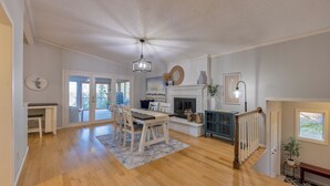 A spacious living room with a fireplace, wooden flooring, and a dining area with a table and chairs. - Beautiful home on Lake Pokegama! (Grand Rapids)