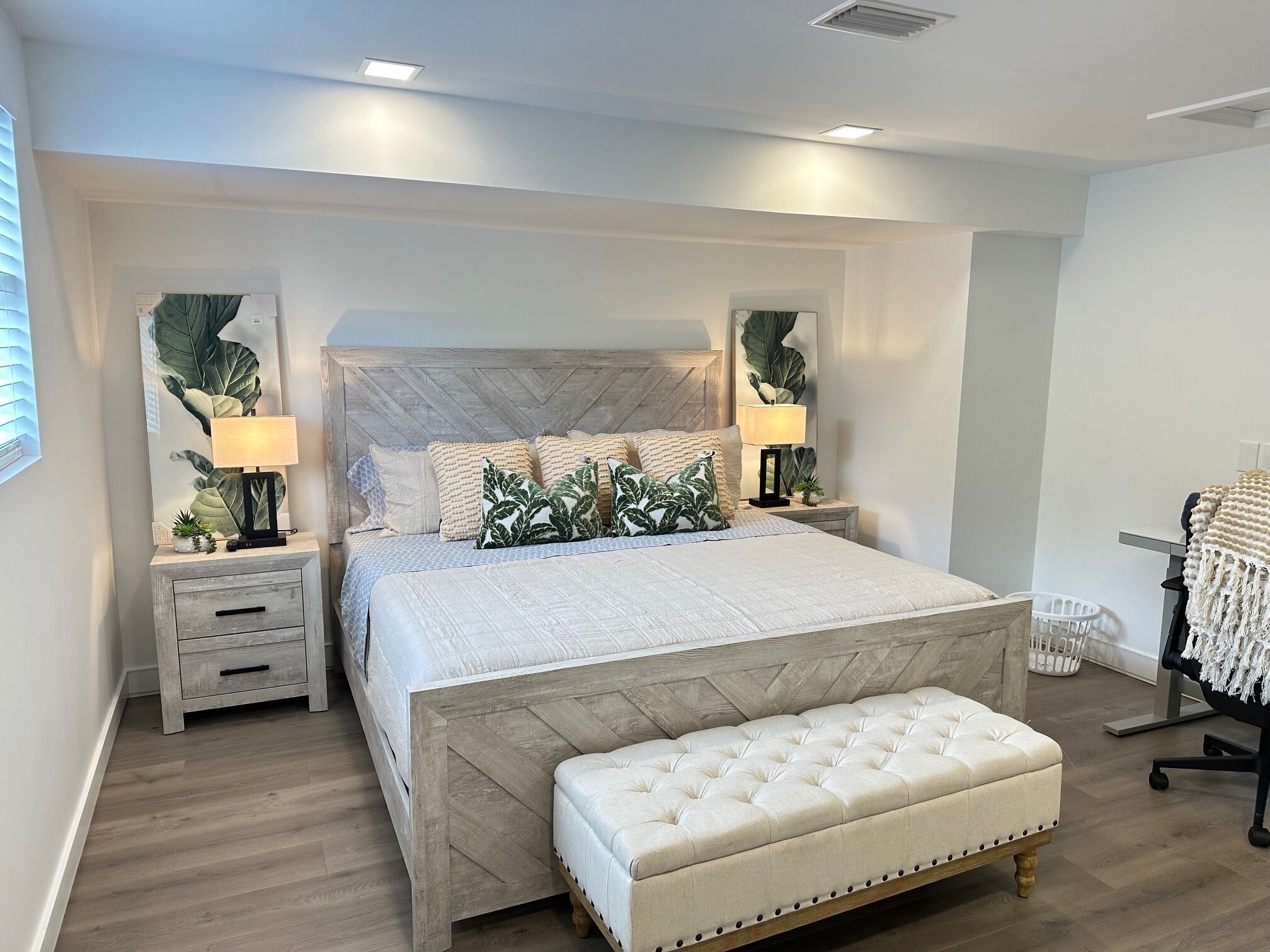 A bedroom with a large bed, two bedside tables, a bench, and a chair.