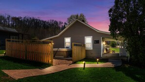 A single-story house with a covered porch, a fenced yard, and a pathway leading to the entrance.