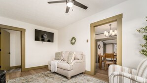 A living room with a beige sofa, a patterned rug, a television, and a ceiling fan.