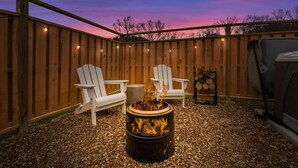 Eine Terrasse im Freien mit zwei Adirondack-Stühlen, einer Feuerstelle und einem Grill.