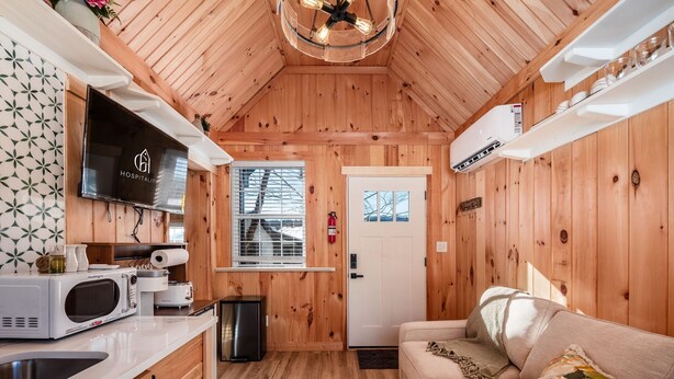 Ein gemütliches Blockhaus-Interieur mit Küche, Wohnbereich und einer Tür, die nach draußen führt.