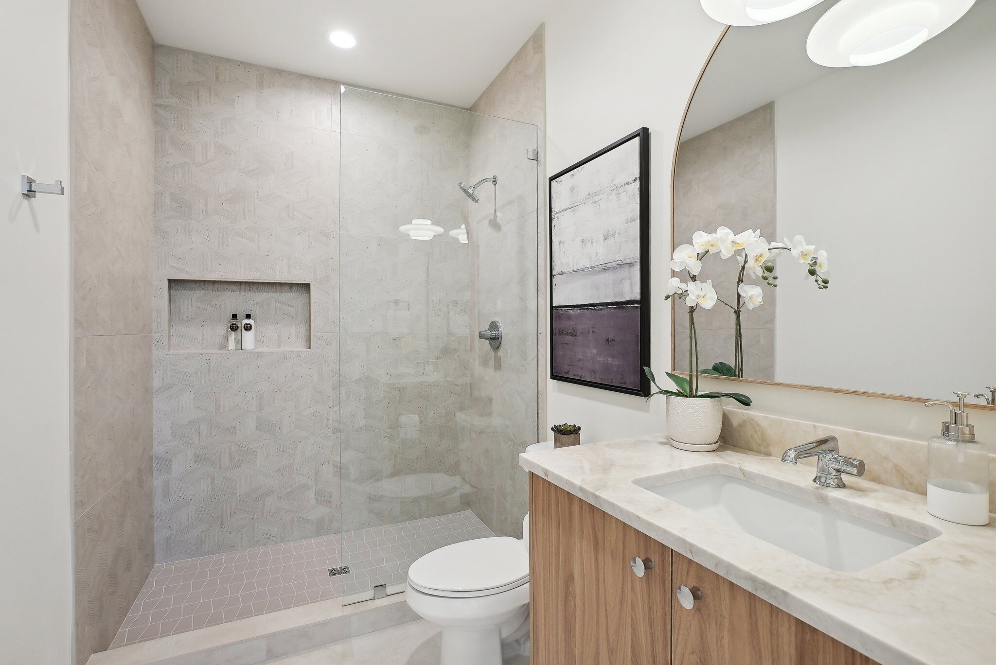 A modern bathroom with a shower, toilet, vanity, and a large mirror.