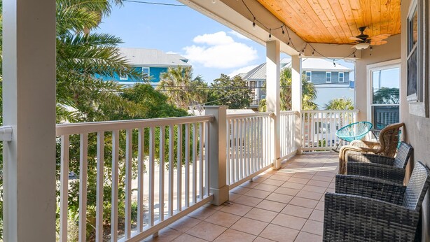 A covered balcony with white railings, wicker furniture, and a ceiling fan. - C's The Day! Second to the beach, 3 Bed Plus loft (Panama City Beach)