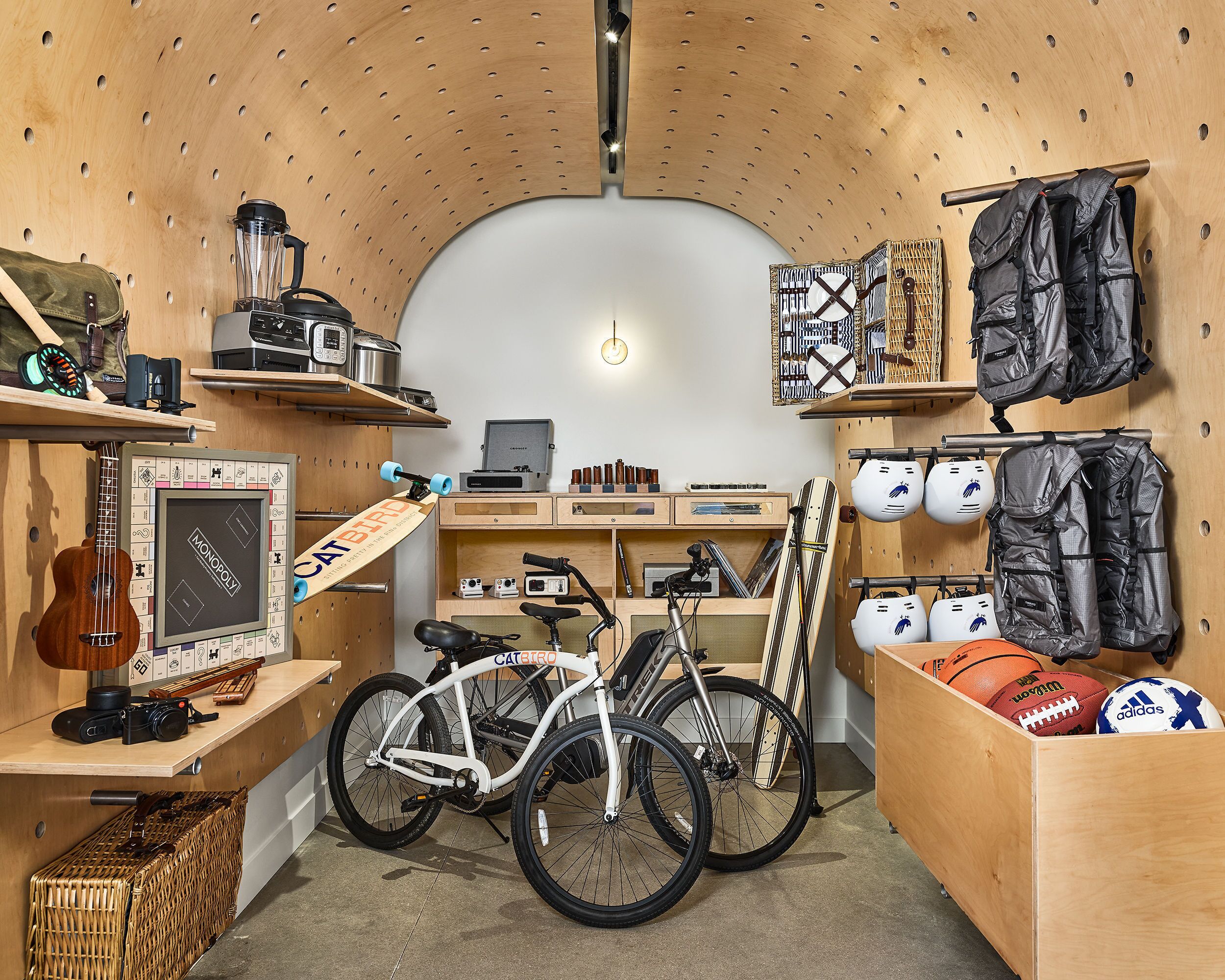 Une pièce de taille modeste avec un plafond en bois, un vélo, une guitare et différents ballons de sport.