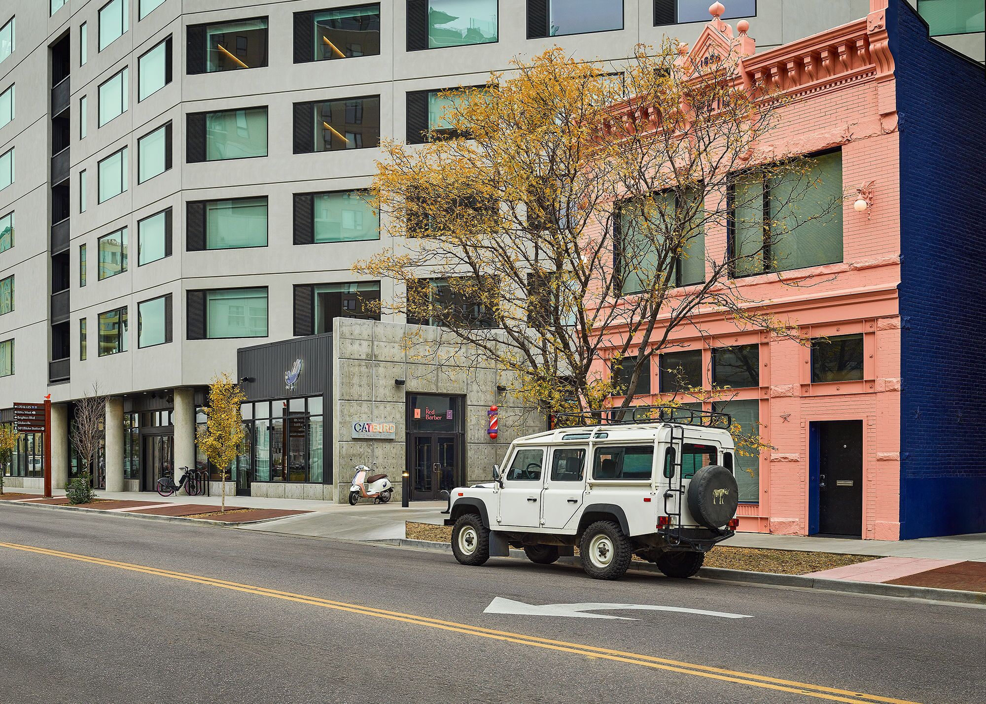 A modern building with a white SUV parked in front.