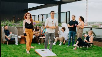 Eine Gruppe von Menschen auf einer Dachterrasse mit Blick auf die Skyline der Stadt.
