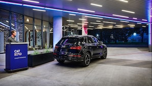 A black SUV parked at a modern building entrance with a blue and purple neon light design on the ceiling and a 'CAT BIRD VALET PARKING' sign.