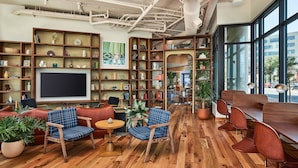 A modern library with wooden floors, bookshelves, and seating areas.
