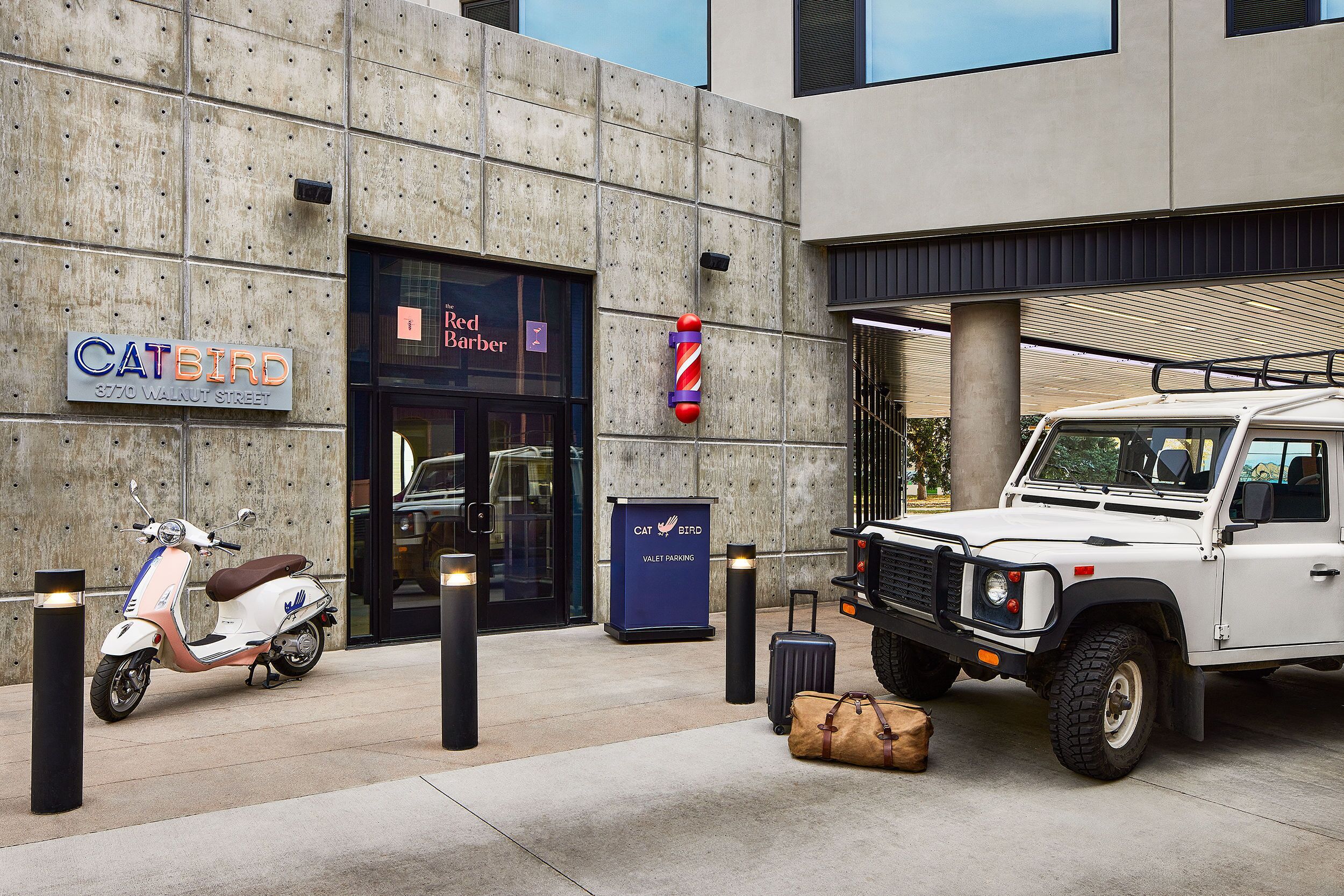 A modern building with a concrete facade, a sign for 'CATBIRD' on the left, and a 'Red Barber' entrance.