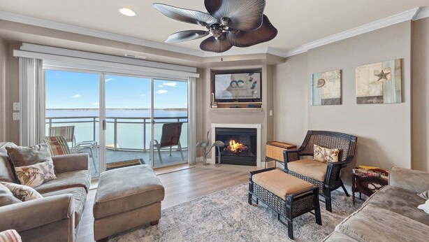A spacious living room with a fireplace, comfortable seating, and a balcony with a view.