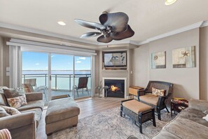 A spacious living room with a fireplace, comfortable seating, and a balcony with a view. - Bella Vista 505 (Ocean City)
