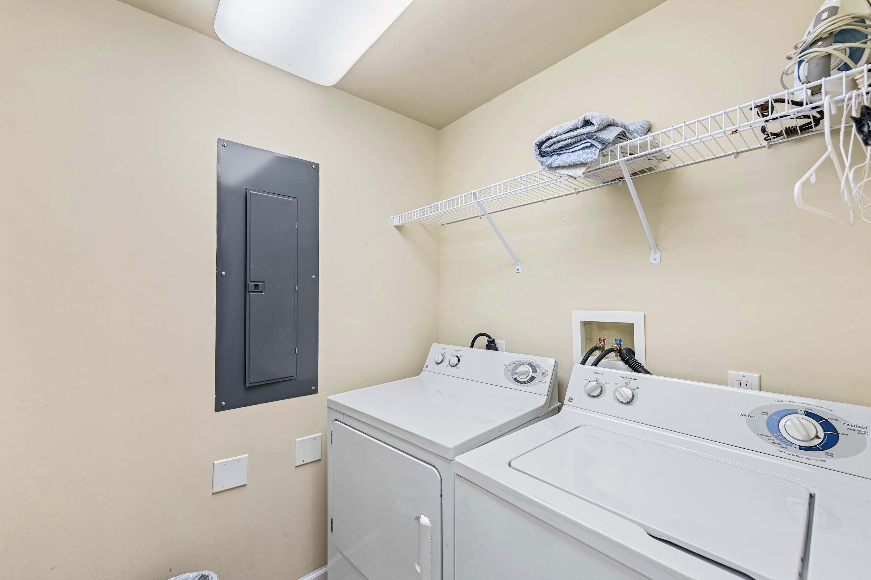 Une buanderie équipée de deux machines à laver et deux sèche-linge superposés, d’un étendoir et d’une porte.