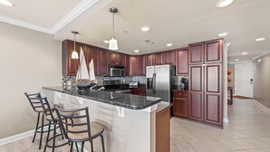 A spacious kitchen with dark wood cabinets, a large island with bar stools, and modern appliances.