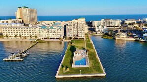 A coastal hotel with a pool, a dock with boats, and a view of the ocean.